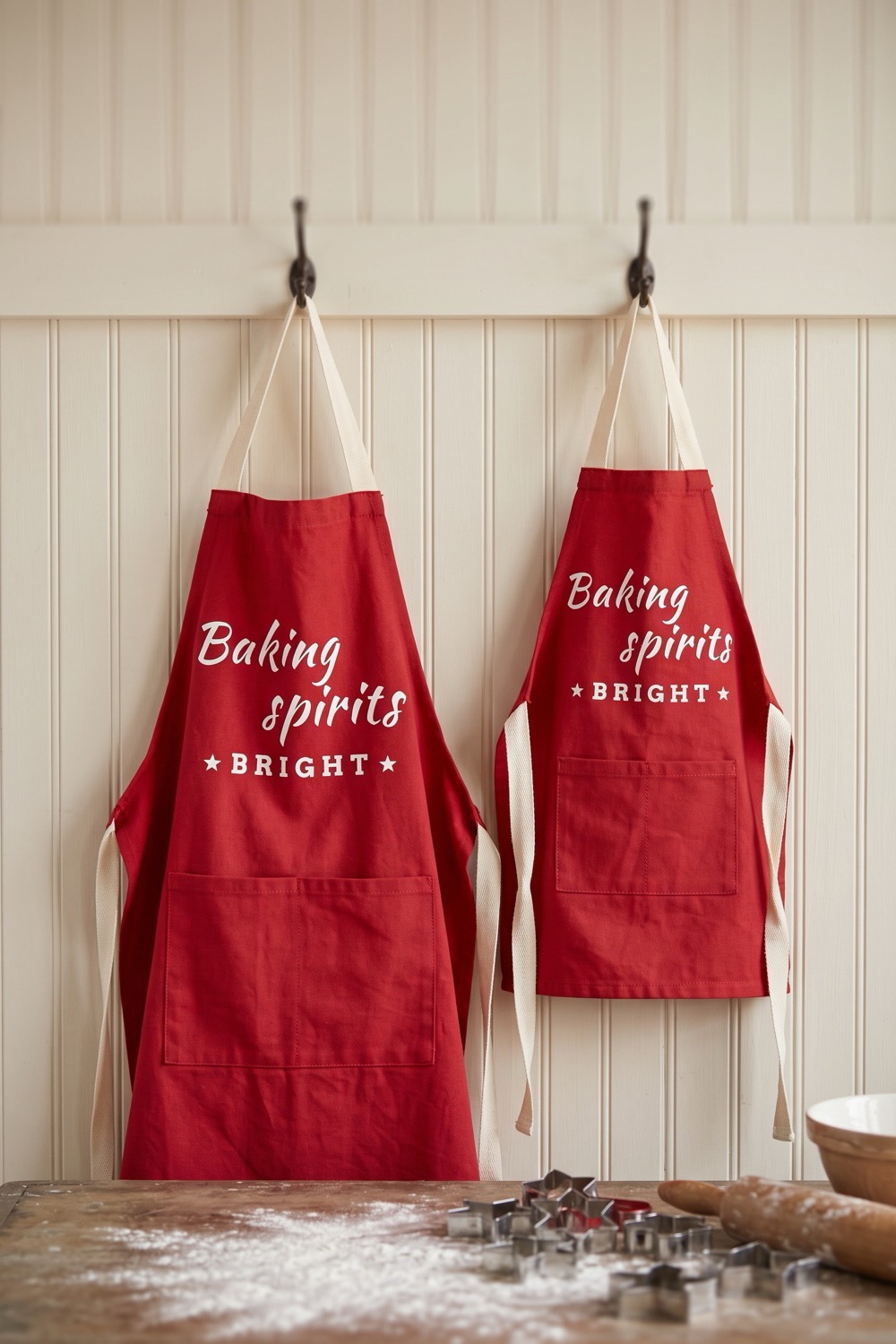 AI-generated picture of an adult and a child red apron side by side with white Baking Spirits Bright lettering